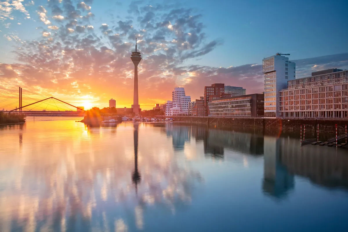 Der Düsseldorfer Medienhafen bei Sonnenuntergang mit dem Rheinturm, den Gehry-Bauten und der Spiegelung im Wasser